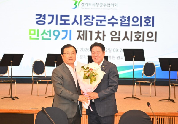 민선9기 경기도시장군수협의회장으로 선출된 최대호 안양시장(오른쪽)이 임시회장으로서 회의를 진행한 이현재 하남시장(왼쪽)으로부터 꽃다발을 받고 있다.jpg